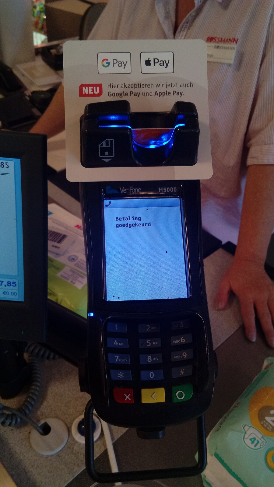 Kartenterminal an einer Ladenkasse mit Hinweisschild auf Apple Pay und Google Pay