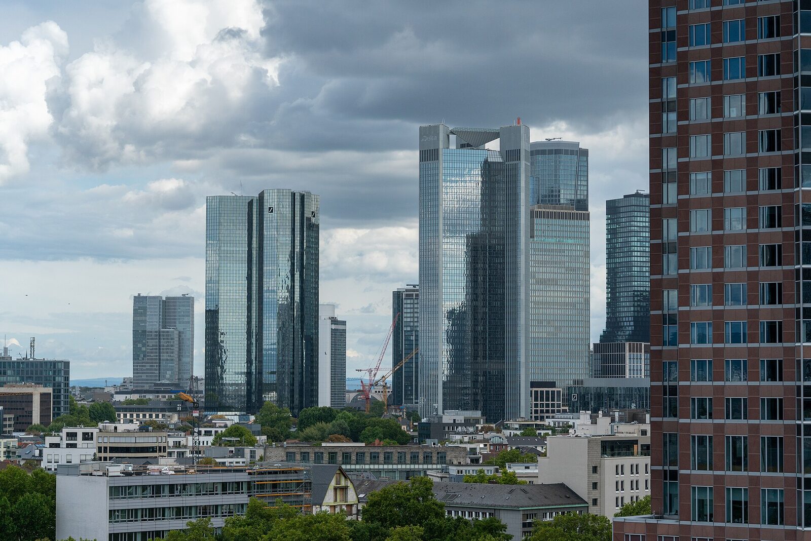 Die Doppeltürme der Deutschen Bank und weitere Hochhäuser des Frankfurter Bankenviertels unter bewölktem Himmel
