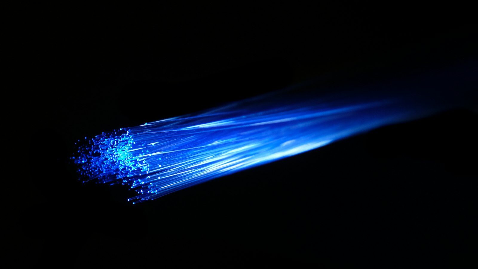 Karanlıkta mavi ışık taşıyan ince fiber optik lif demeti