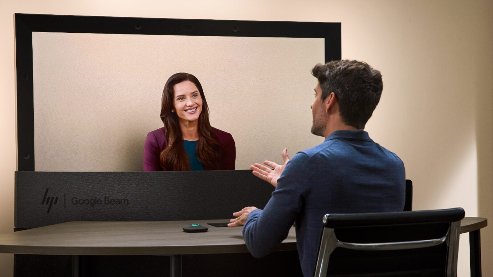 Zwei Personen sprechen über ein HP-Dimension-Gerät mit Google Beam; die Gesprächspartnerin erscheint dreidimensional auf dem großen Bildschirm