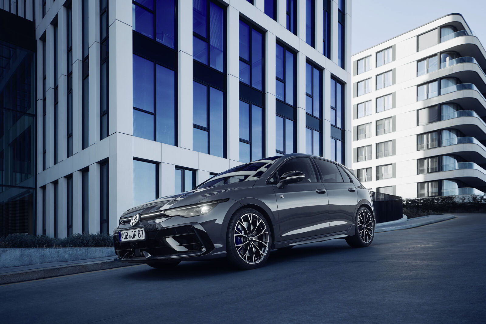 Gri Volkswagen Golf R, modern binaların önünde önden-yandan görünüm