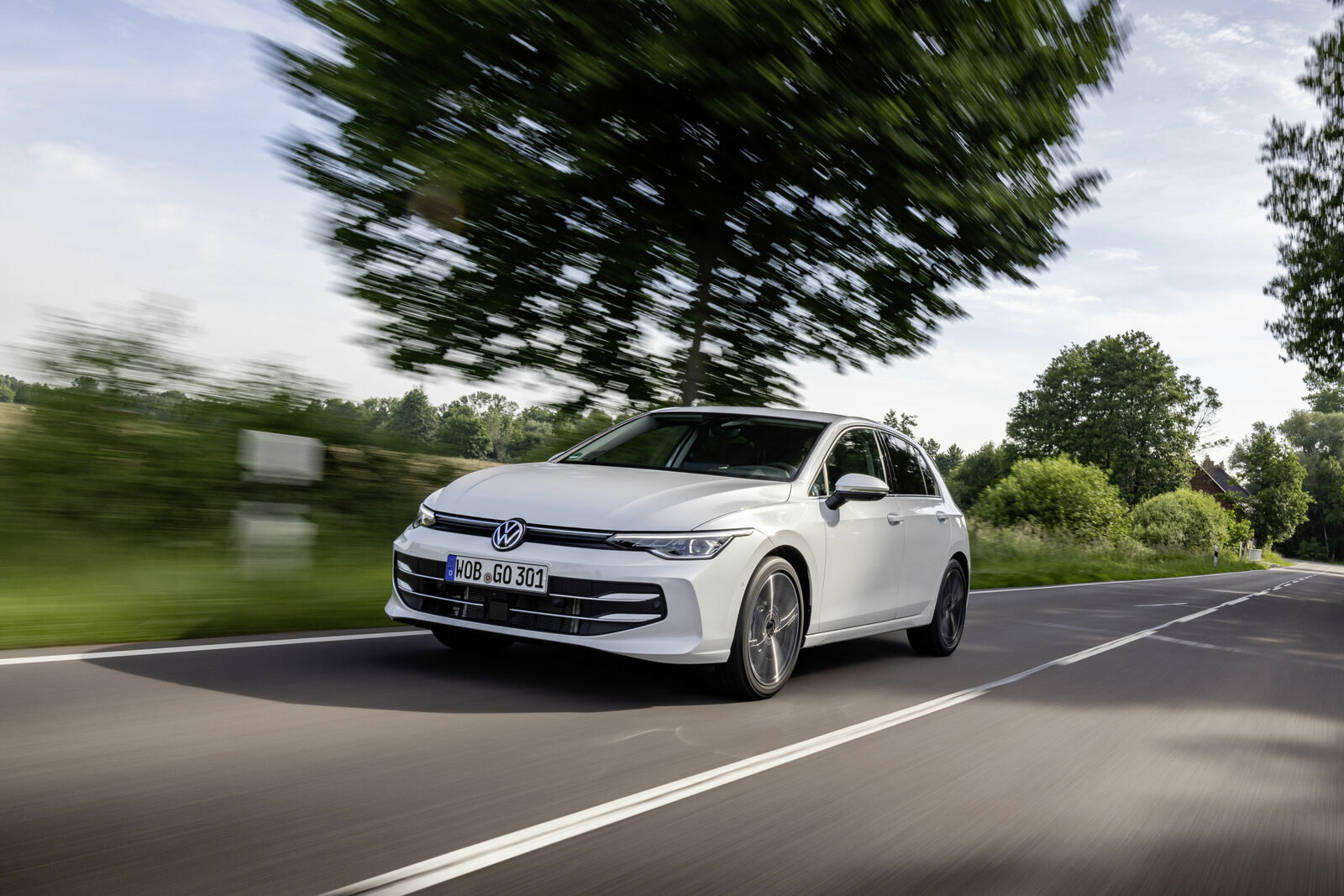 Beyaz Volkswagen Golf, kırsal bir yolda ilerlerken önden-yandan görünüm