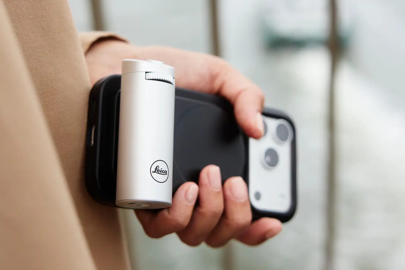Hand hält ein iPhone mit angesetztem silbernem Leica LUX Grip