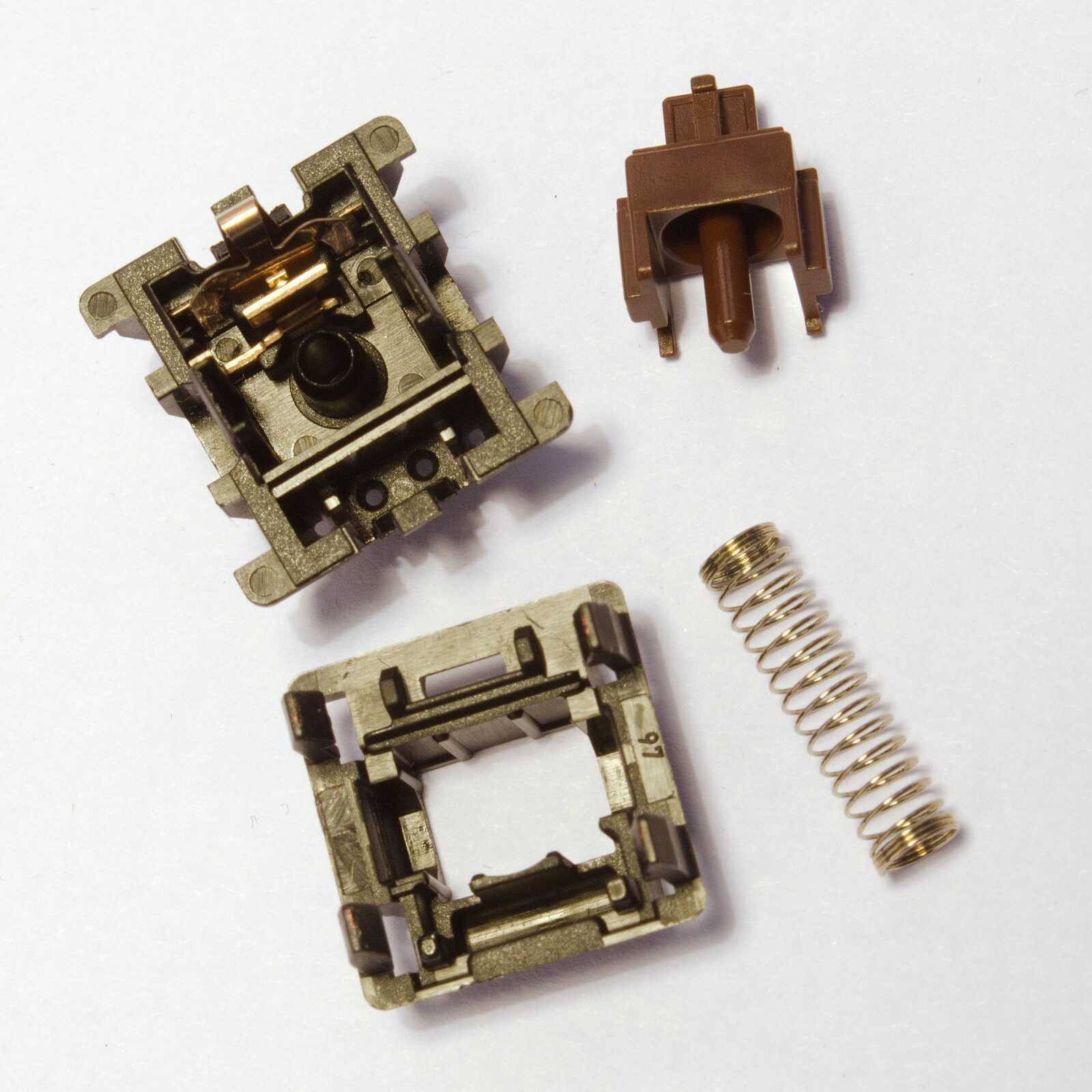 Parçalarına ayrılmış bir Cherry MX Brown switch: gövde üstü, gövde altı, sap ve yay