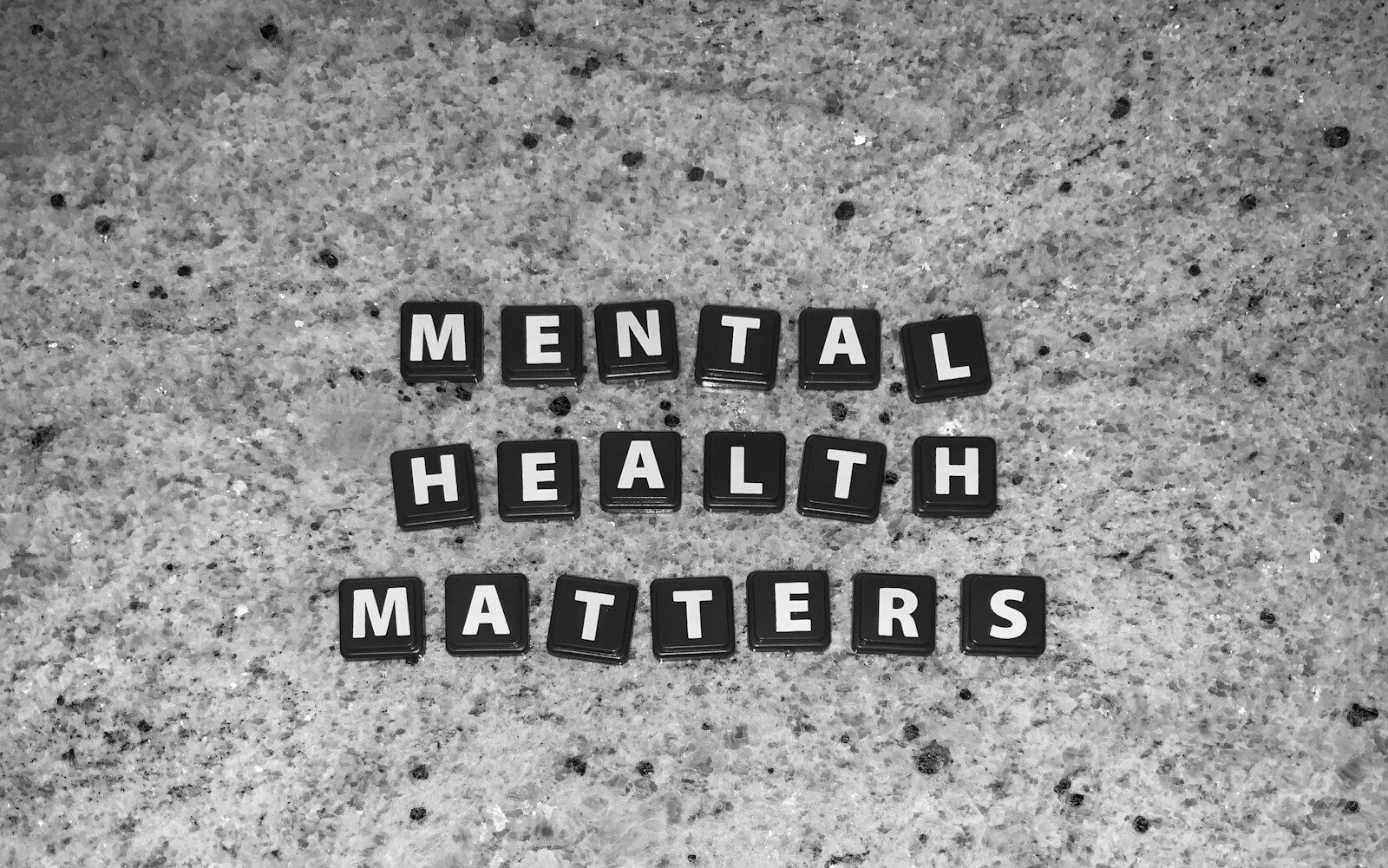 Schwarze Buchstabensteine mit den Worten „Mental Health Matters“ auf grauem Steinuntergrund, Symbolbild