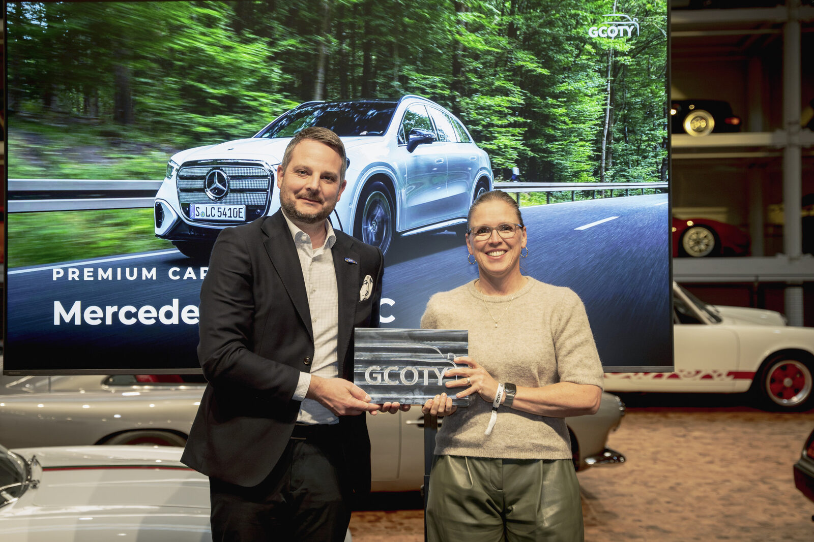 Vertreter von Mercedes-Benz und der GCOTY-Jury mit der Auszeichnung vor einer Leinwand mit dem elektrischen GLC