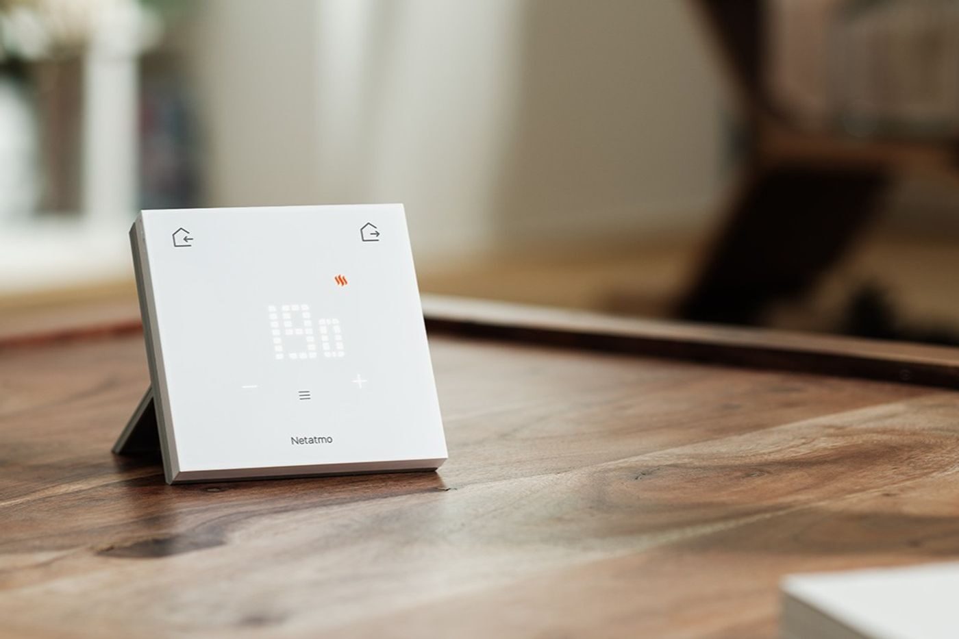 Il Termostato ORIGINAL di Netatmo appoggiato su un tavolo in legno con il display acceso