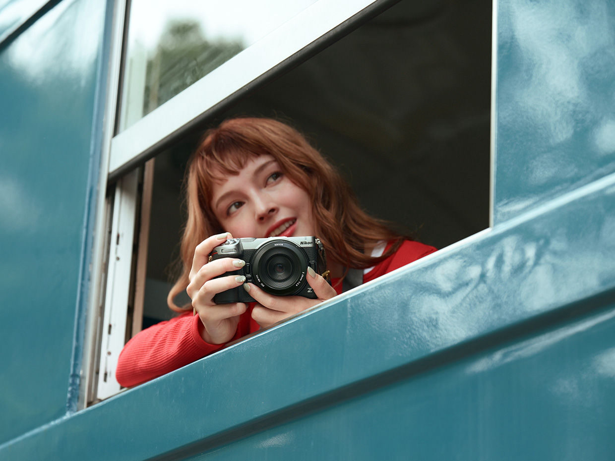 Frau fotografiert mit einer silbernen Nikon Z5IIC aus einem Zugfenster