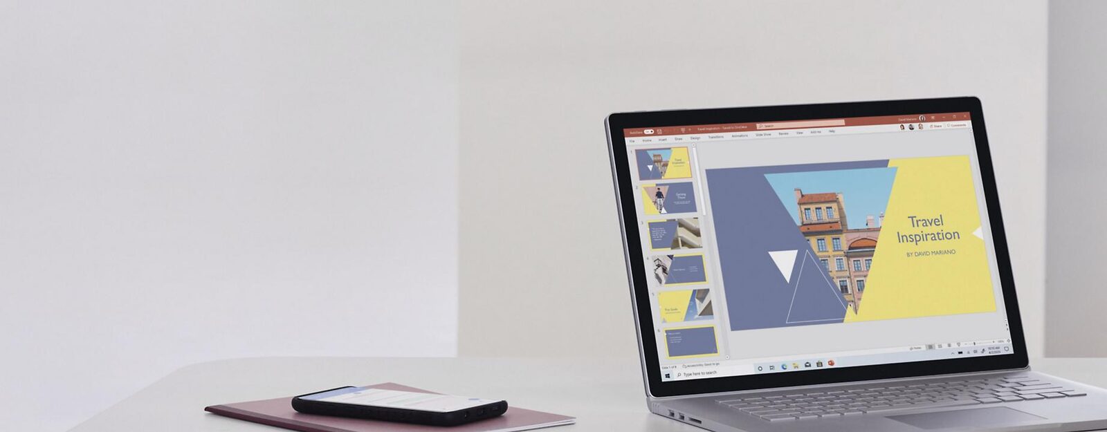 Laptop mit geöffneter PowerPoint-Präsentation und Smartphone auf einem hellen Schreibtisch