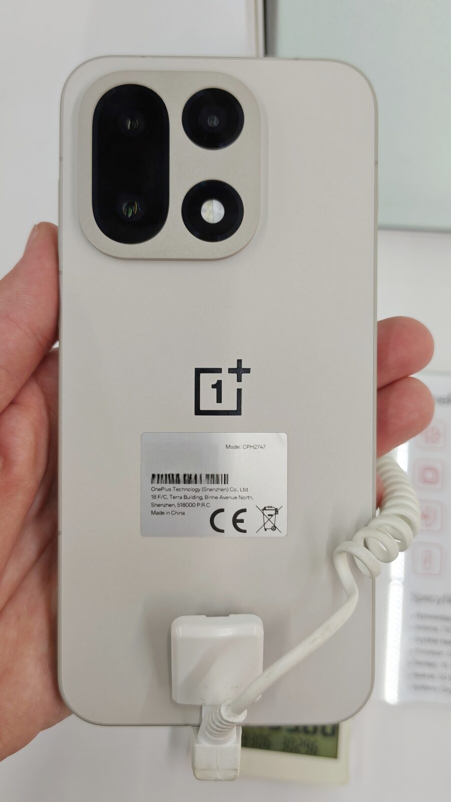 Achterkant van een OnePlus 15 in de kleur Sand Storm met de cameramodule linksboven