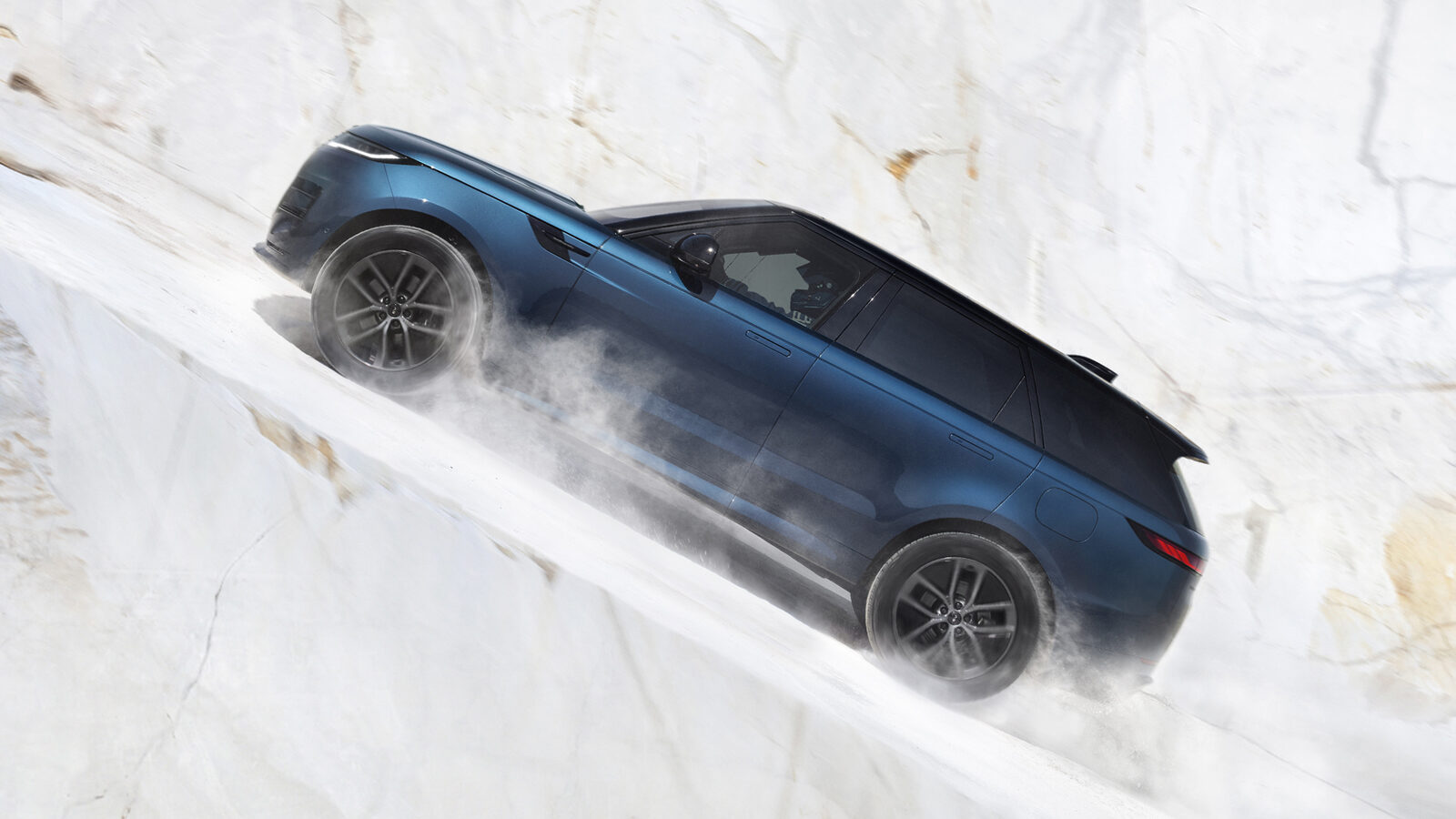 Lacivert Range Rover Sport Electric, beyaz mermer ocağında dik bir yokuşu toz kaldırarak tırmanıyor