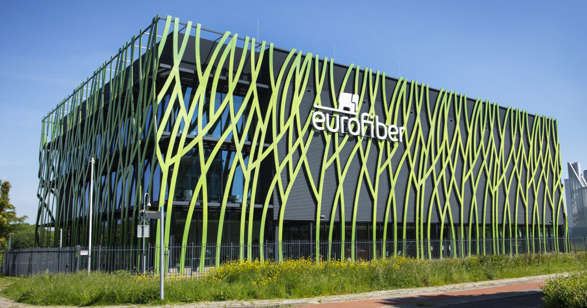 Het datacenter van Eurofiber in Groningen met een gevel van groene, grillige lamellen tegen een blauwe lucht