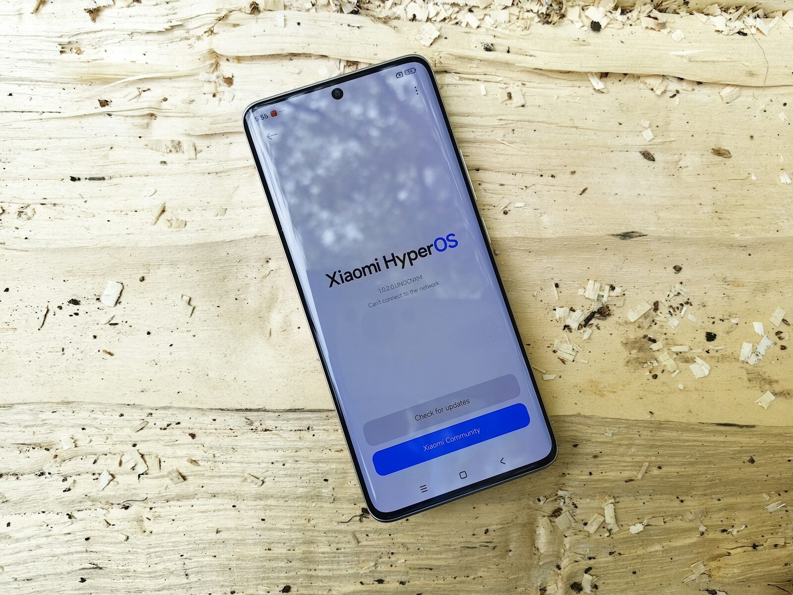 Ahşap zemin üzerinde duran, ekranında yazılım güncelleme sayfası açık bir Android telefon