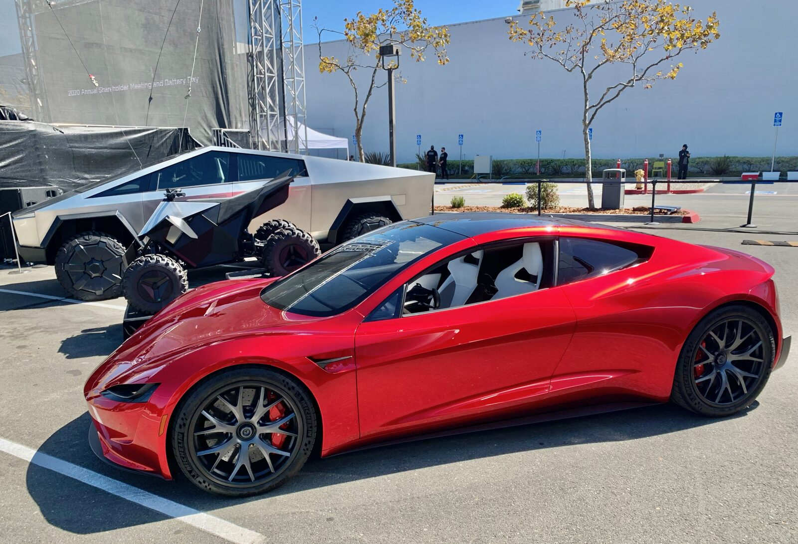 Tesla genel merkezinde sergilenen kırmızı ikinci nesil Tesla Roadster, arkasında Cybertruck konsepti