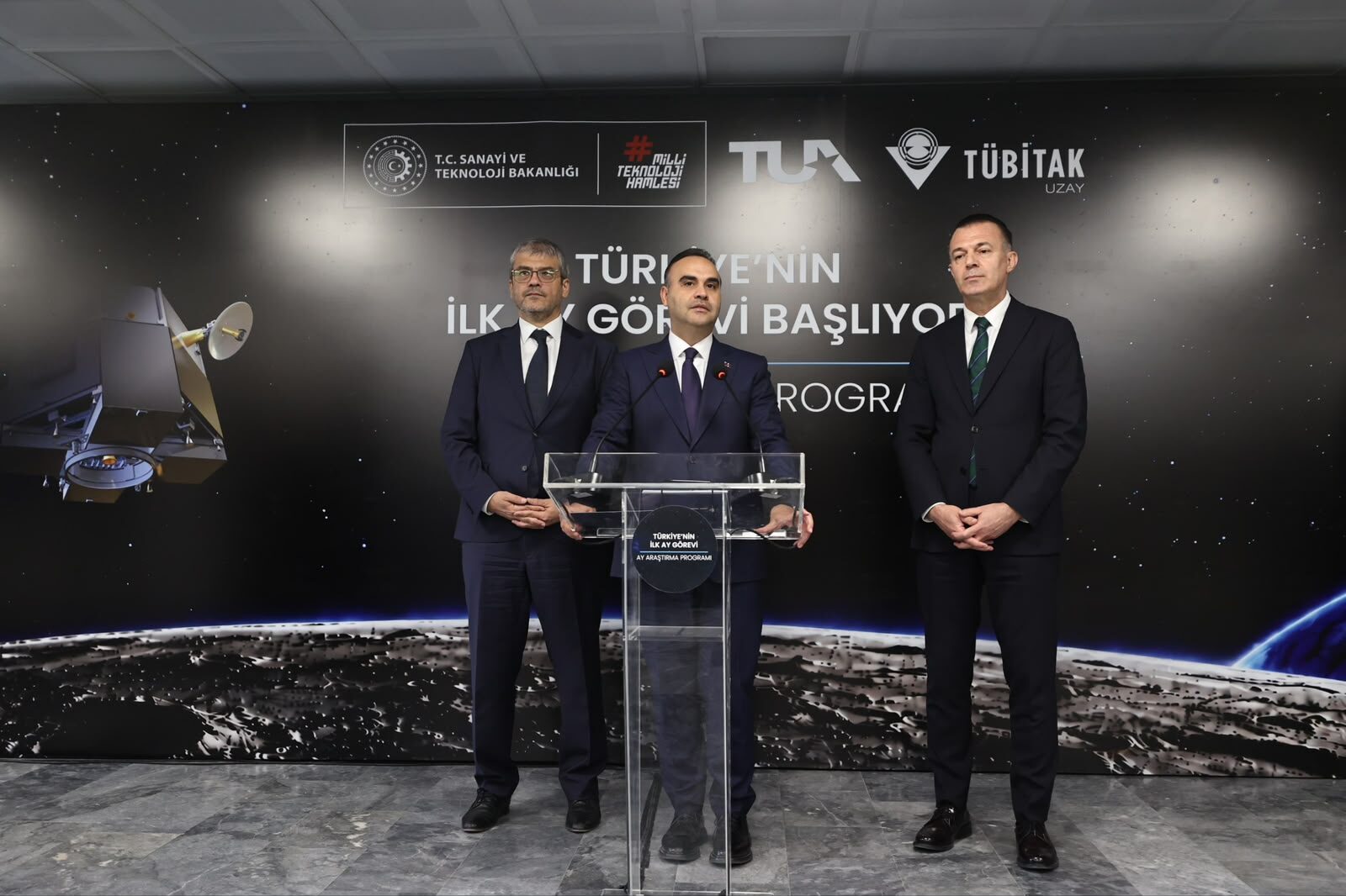 Sanayi ve Teknoloji Bakanı Mehmet Fatih Kacır, arkasında Ay Uzay Aracı çizimi ve "Türkiye'nin ilk Ay görevi başlıyor" yazısı bulunan kürsüde açıklama yapıyor