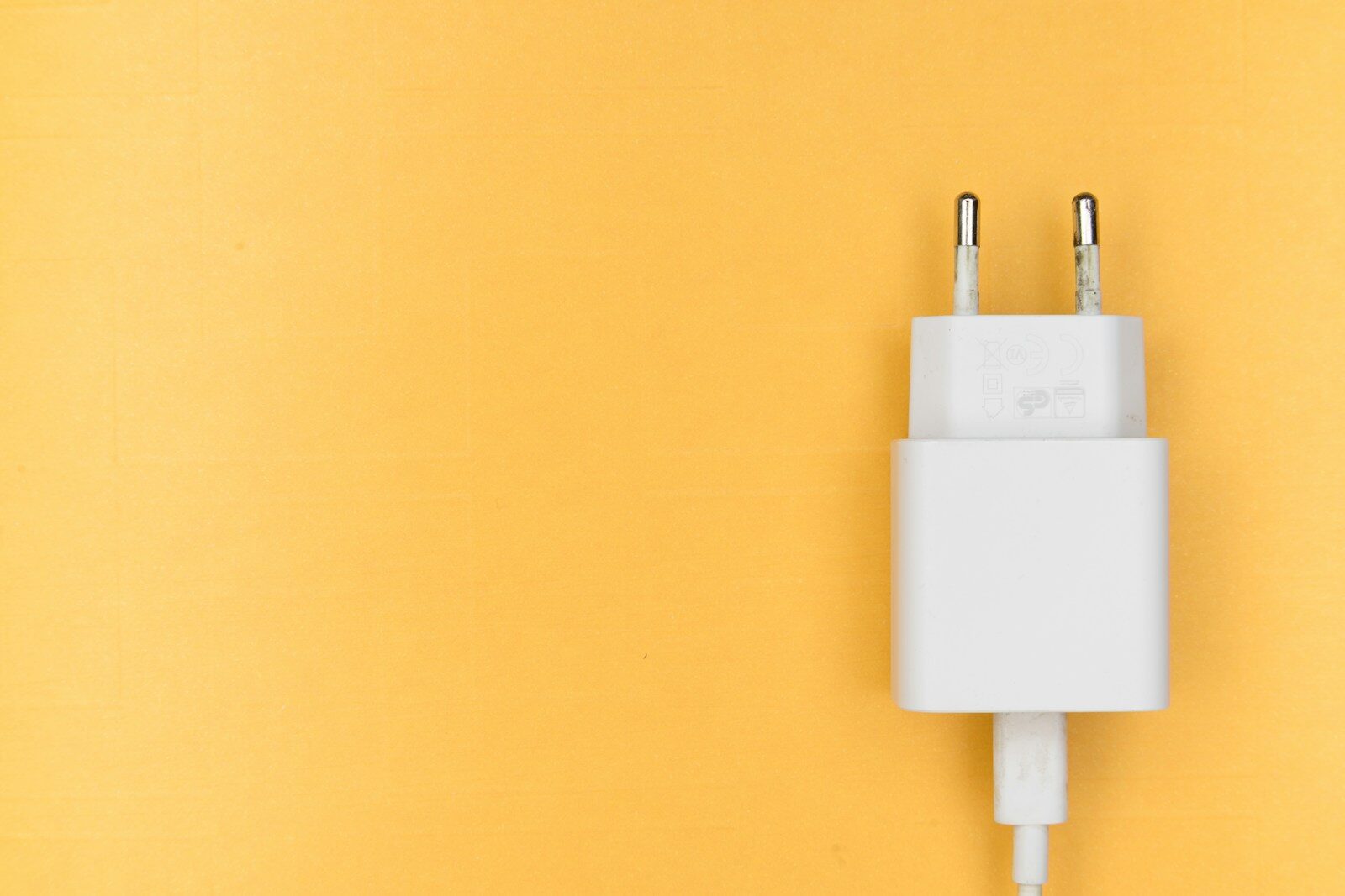 Weißes USB-C-Netzteil mit Eurostecker und Kabel auf gelbem Hintergrund