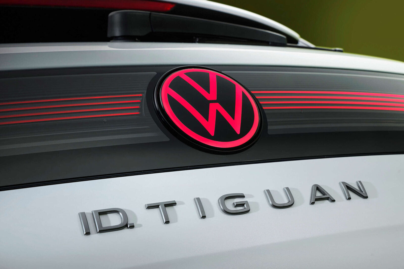 Heck des ID. Tiguan mit rot beleuchtetem VW-Logo, roter Leuchtleiste und dem Schriftzug ID. TIGUAN