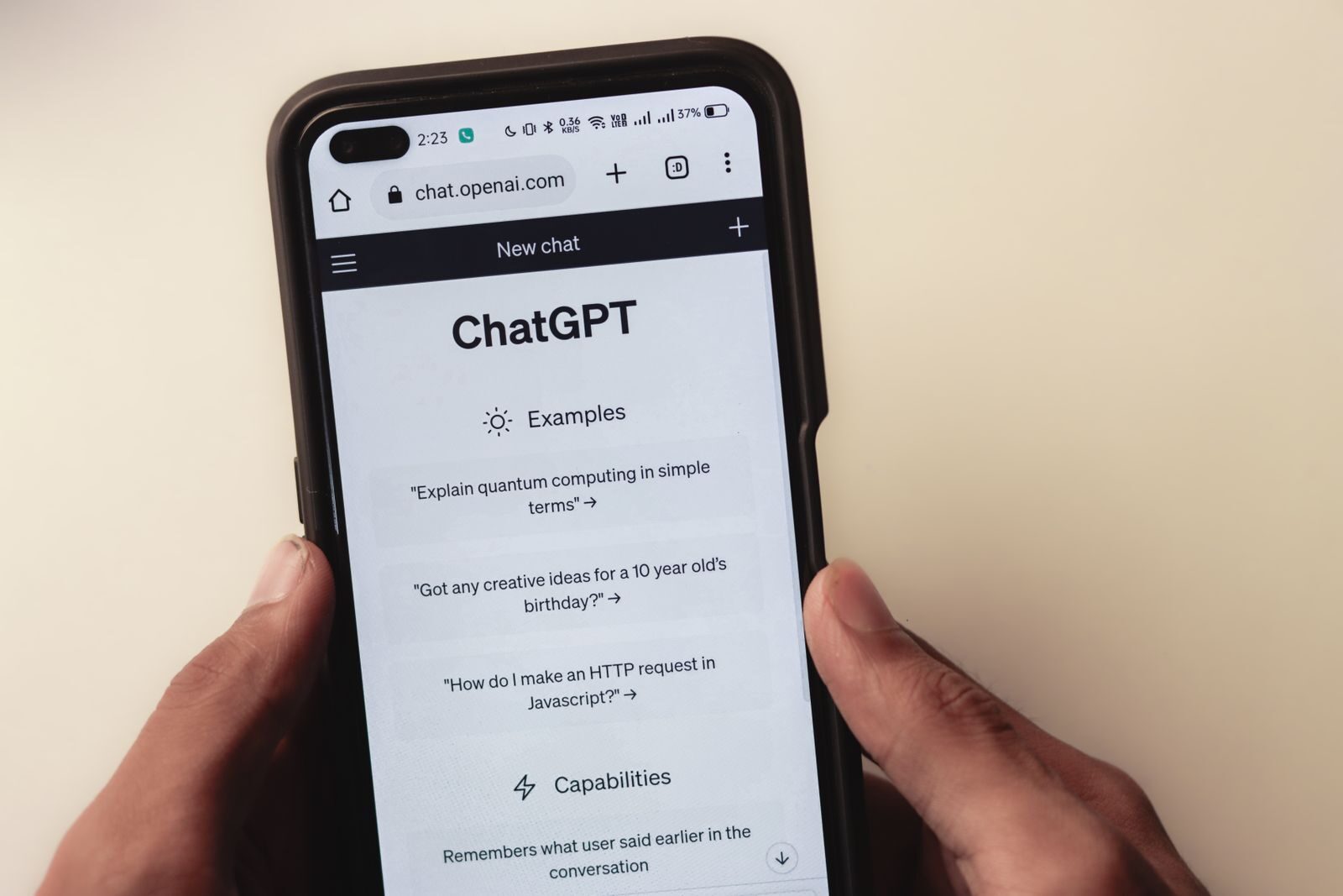 İki elle tutulan akıllı telefonun ekranında açık ChatGPT sohbet sayfası