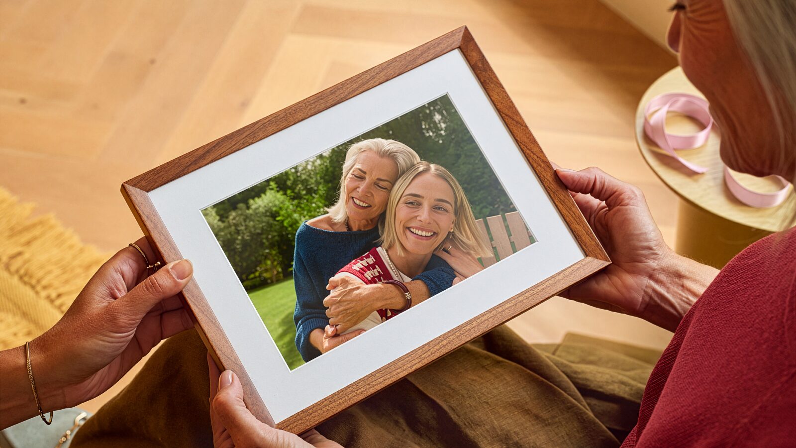 Una persona tiene tra le mani l'Alexa Photo Frame con cornice in legno di noce e passe-partout bianco