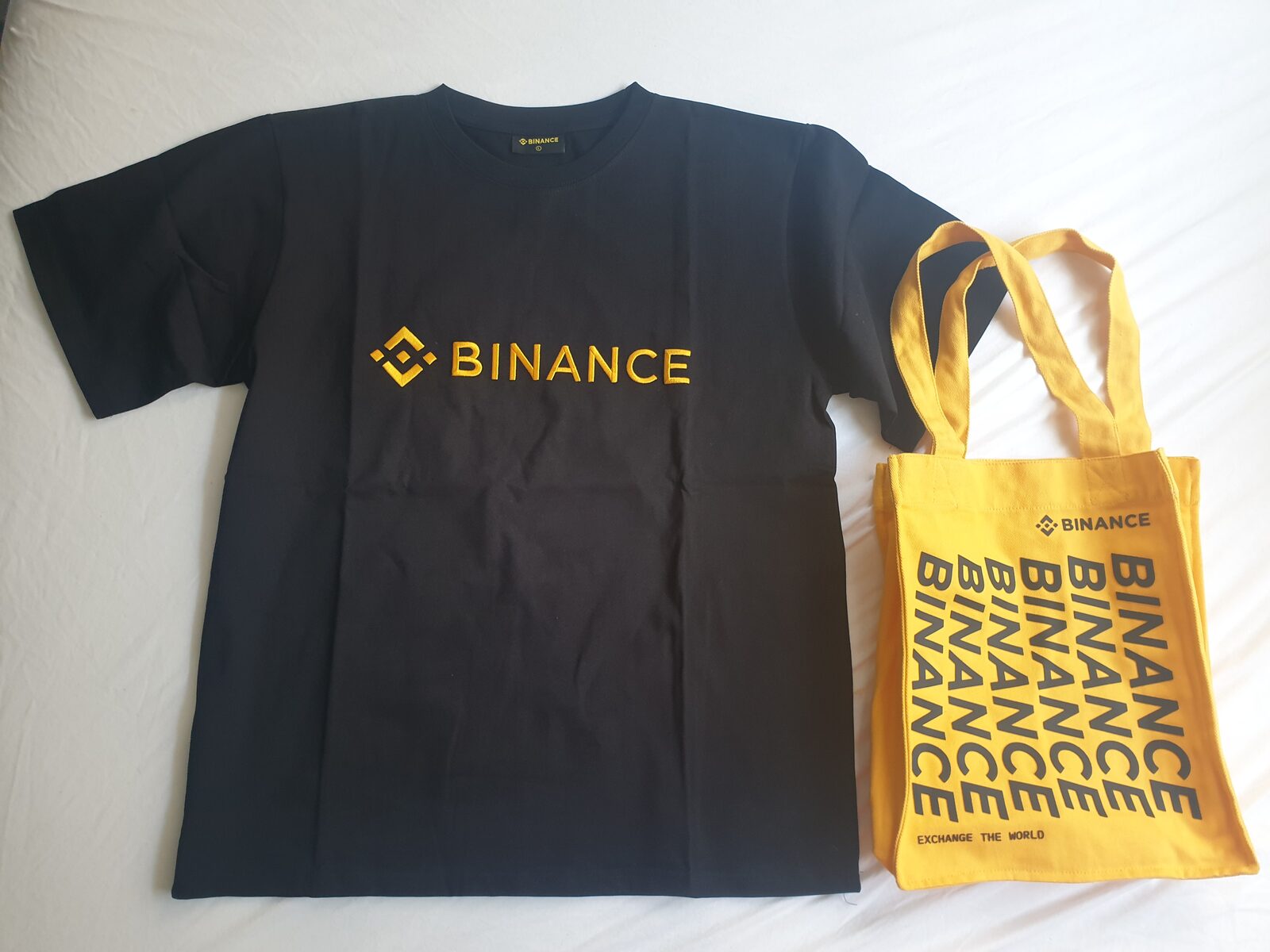 Binance logolu siyah tişört ve sarı bez çanta