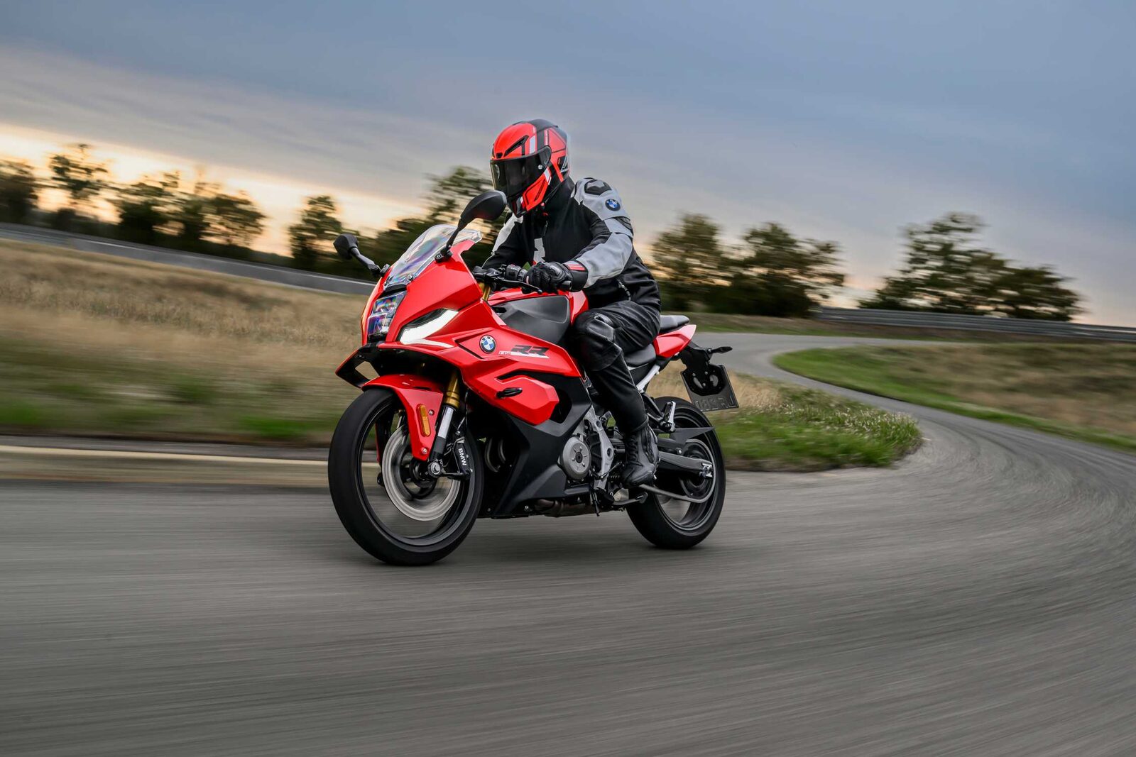 Kırmızı BMW F 450 RR, kask takan bir sürücüyle pistte virajı dönerken