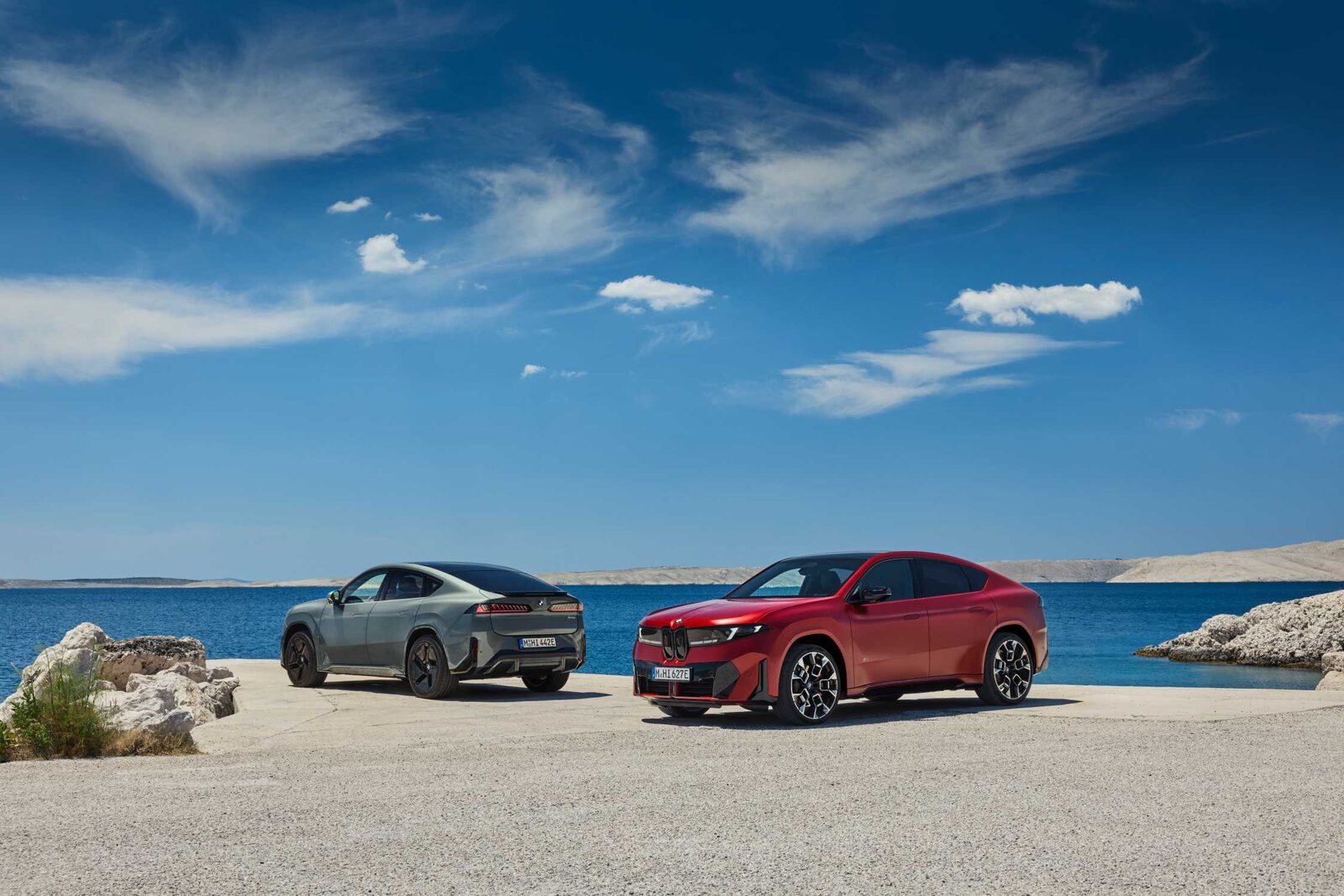 İki BMW iX4: kırmızı ve gri SUV-coupe'lar deniz kenarında