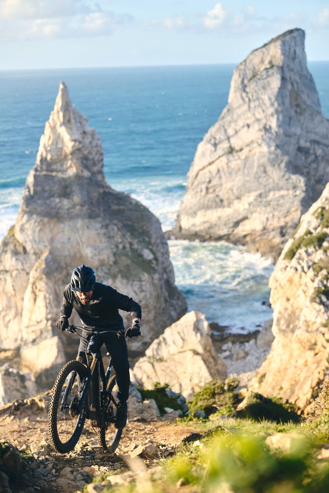 Een mountainbiker op een e-bike met Bosch-middenmotor op een rotsachtig kustpad