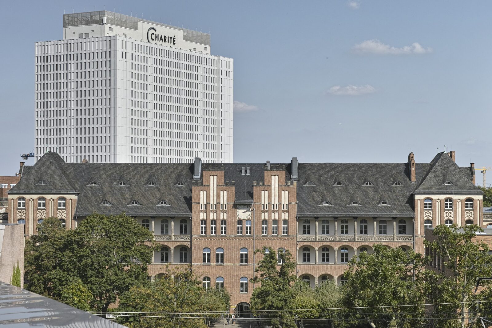 Historisches Backsteingebäude auf dem Campus Charité Mitte, dahinter das Bettenhochhaus mit Charité-Schriftzug