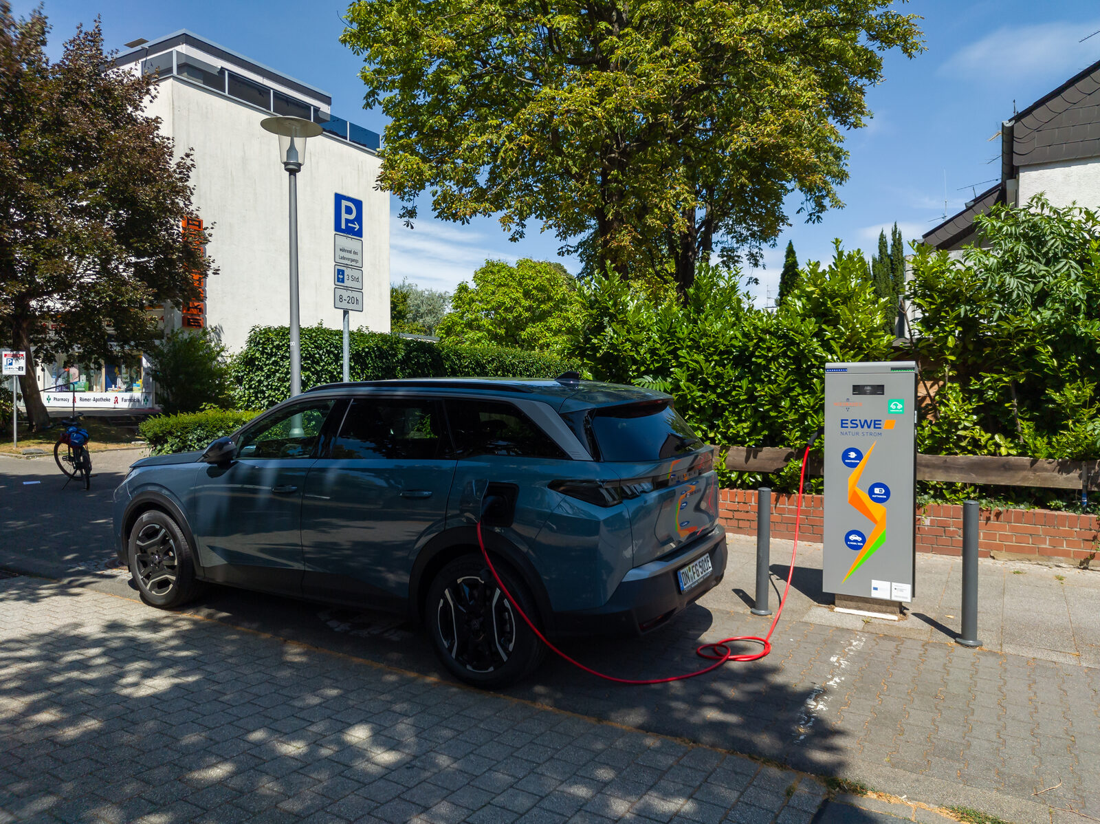 Ein blaues Elektro-SUV lädt an einer öffentlichen Ladesäule am Straßenrand in Wiesbaden