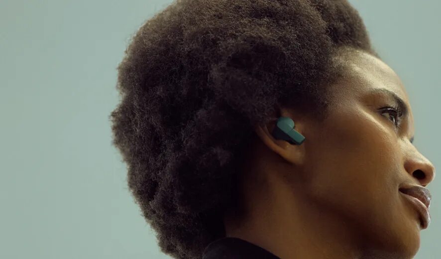 Una donna di profilo con un auricolare Fairbuds 2 verde nell'orecchio