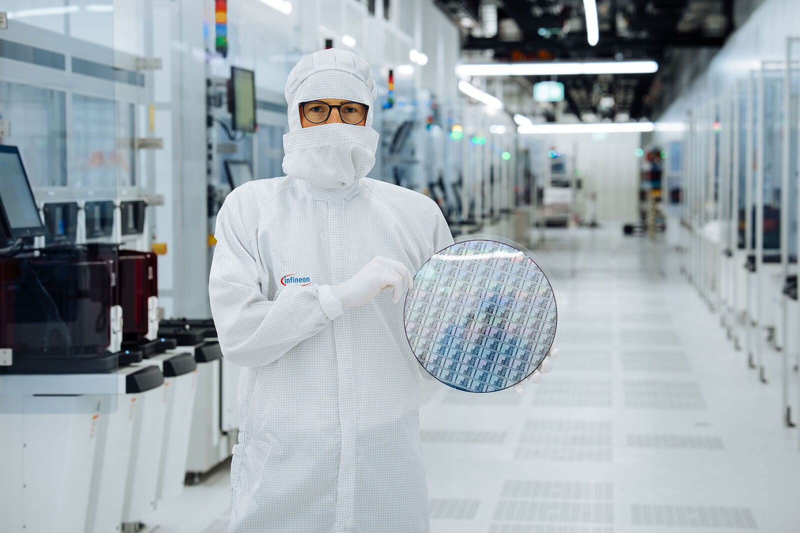 Mitarbeiter im Reinraumanzug hält einen 300-Millimeter-Galliumnitrid-Wafer im Infineon-Werk Villach
