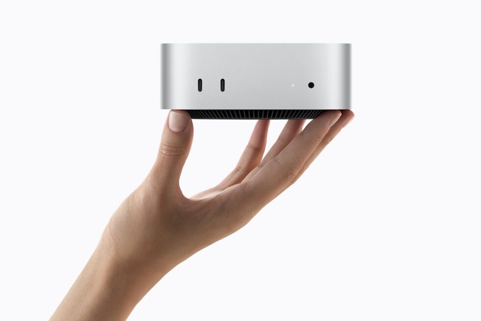 Elle tutulan gümüş rengi Apple Mac mini, önden USB-C portları görünür şekilde