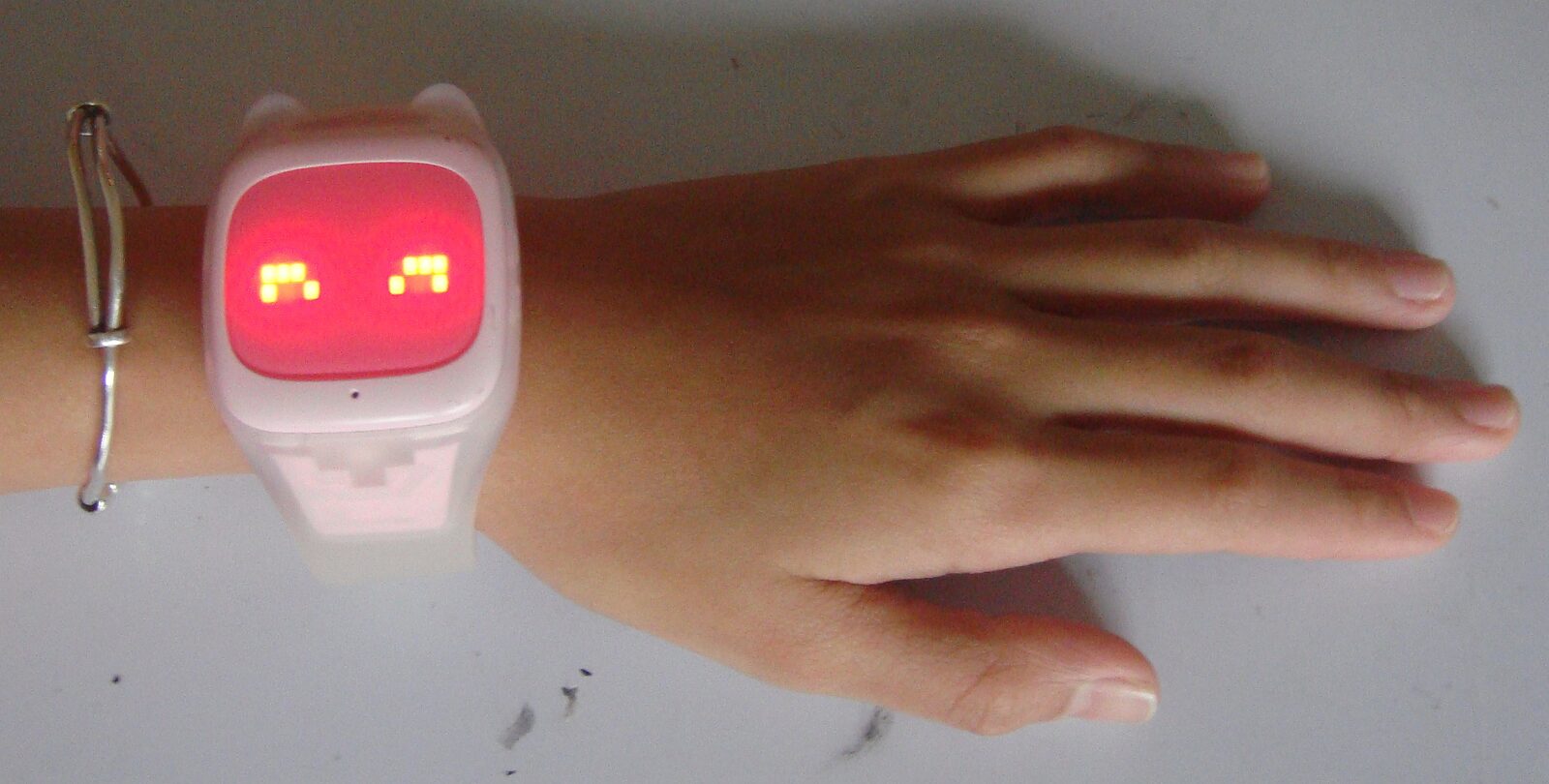 Kinder-Smartwatch in Rosa mit leuchtendem Display am Handgelenk eines Kindes