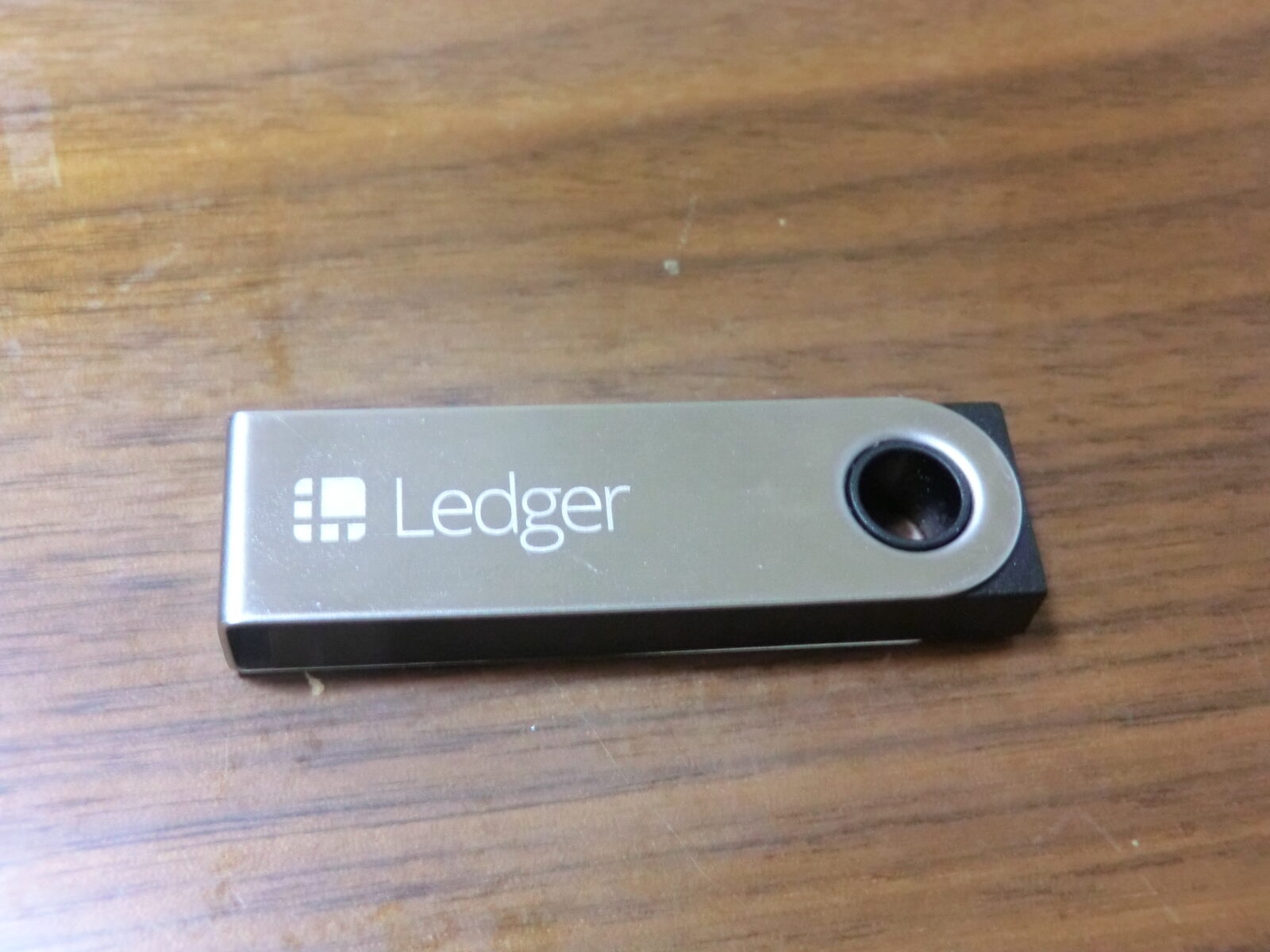 Ein Ledger Nano S Hardware-Wallet mit Metallabdeckung auf einem Holztisch