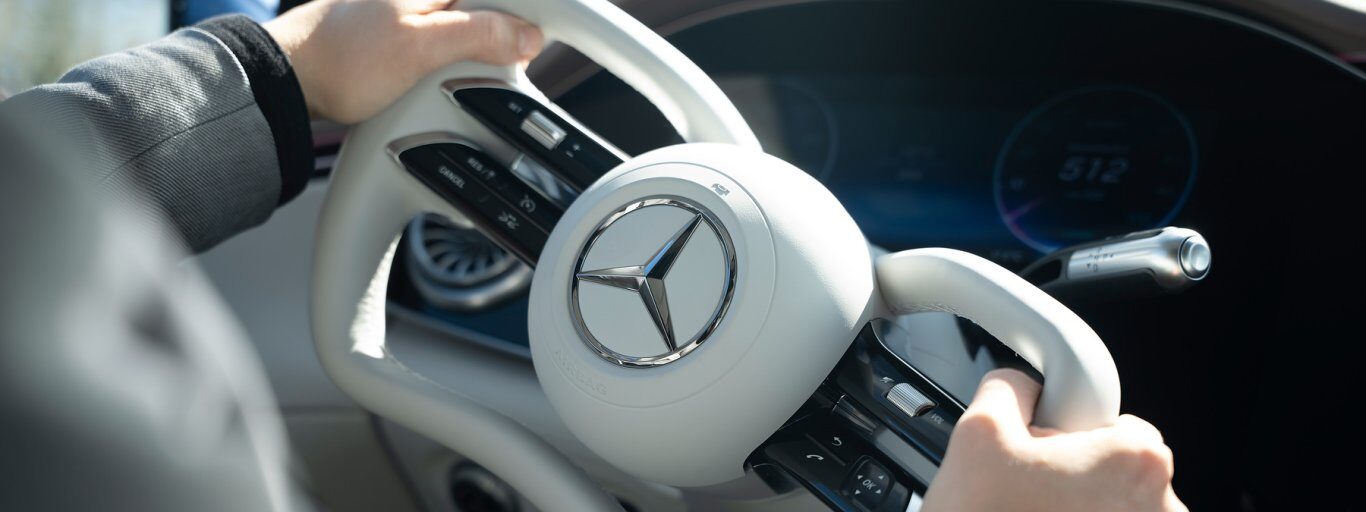 Hände am abgeflachten, beigen Lenkrad des Mercedes EQS mit Steer-by-Wire