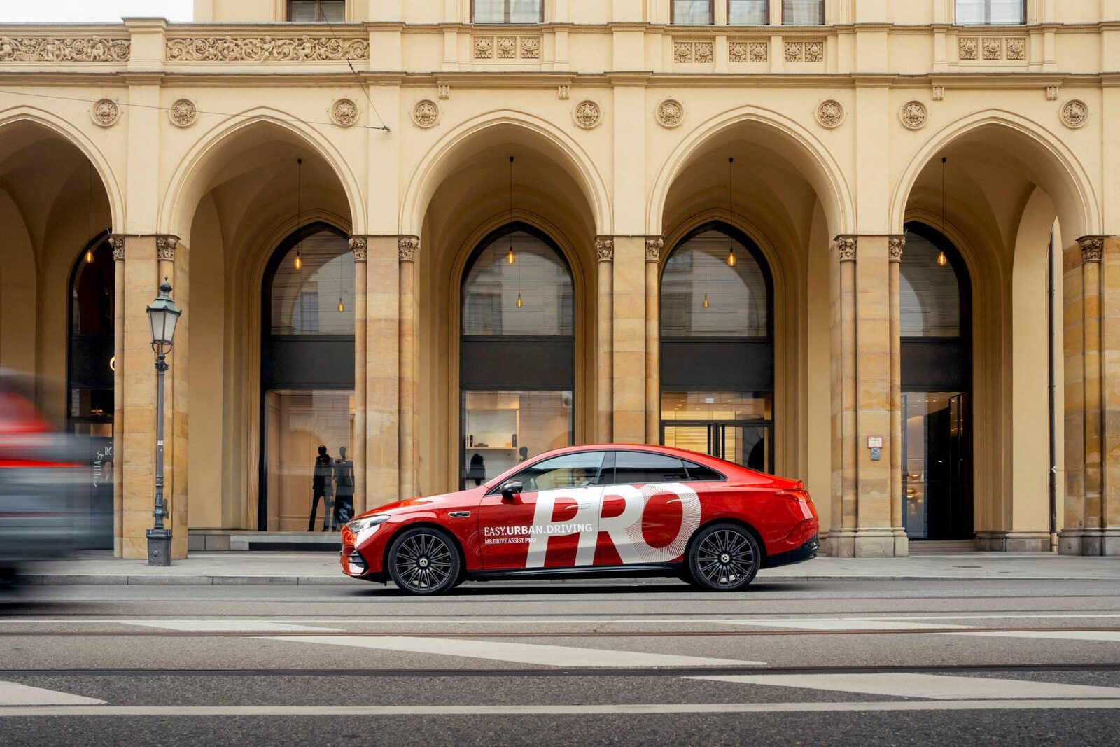 Mercedes-Testfahrzeug mit MB.DRIVE ASSIST PRO vor einer Arkadenfassade in München