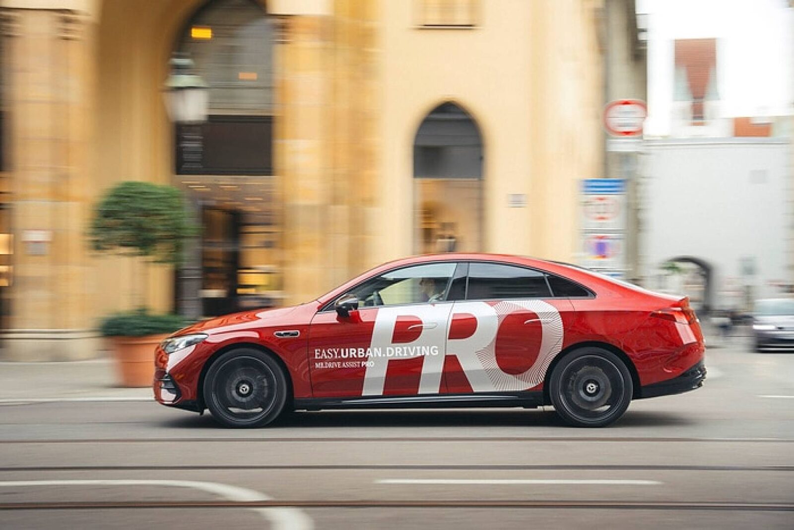 Roter Mercedes mit „PRO“-Folierung fährt durch eine Münchner Innenstadtstraße