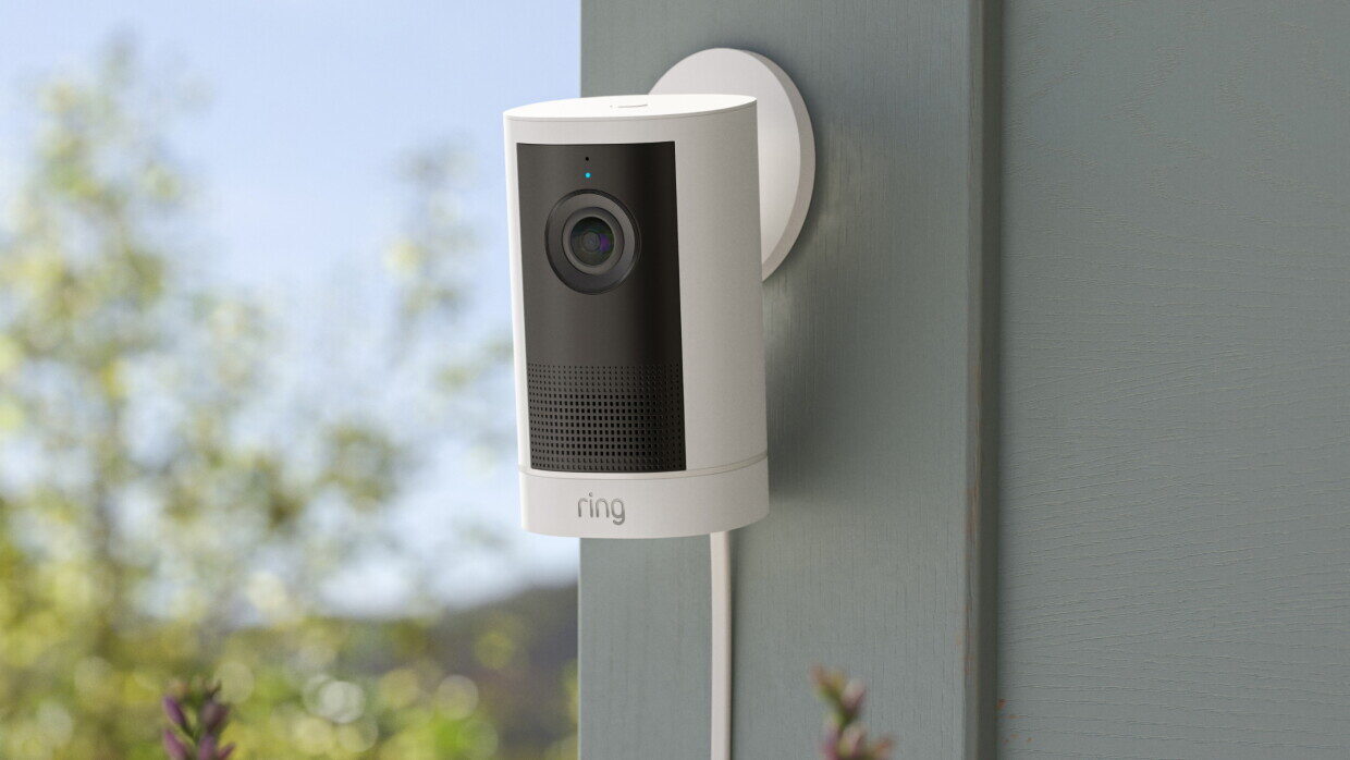 La nuova Ring Outdoor Cam 4K Plus bianca fissata alla parete esterna di una casa