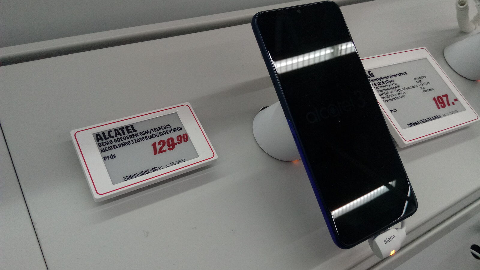 Smartphone auf einem Diebstahlschutz-Ständer in einem Elektronikmarkt, daneben elektronische Preisschilder