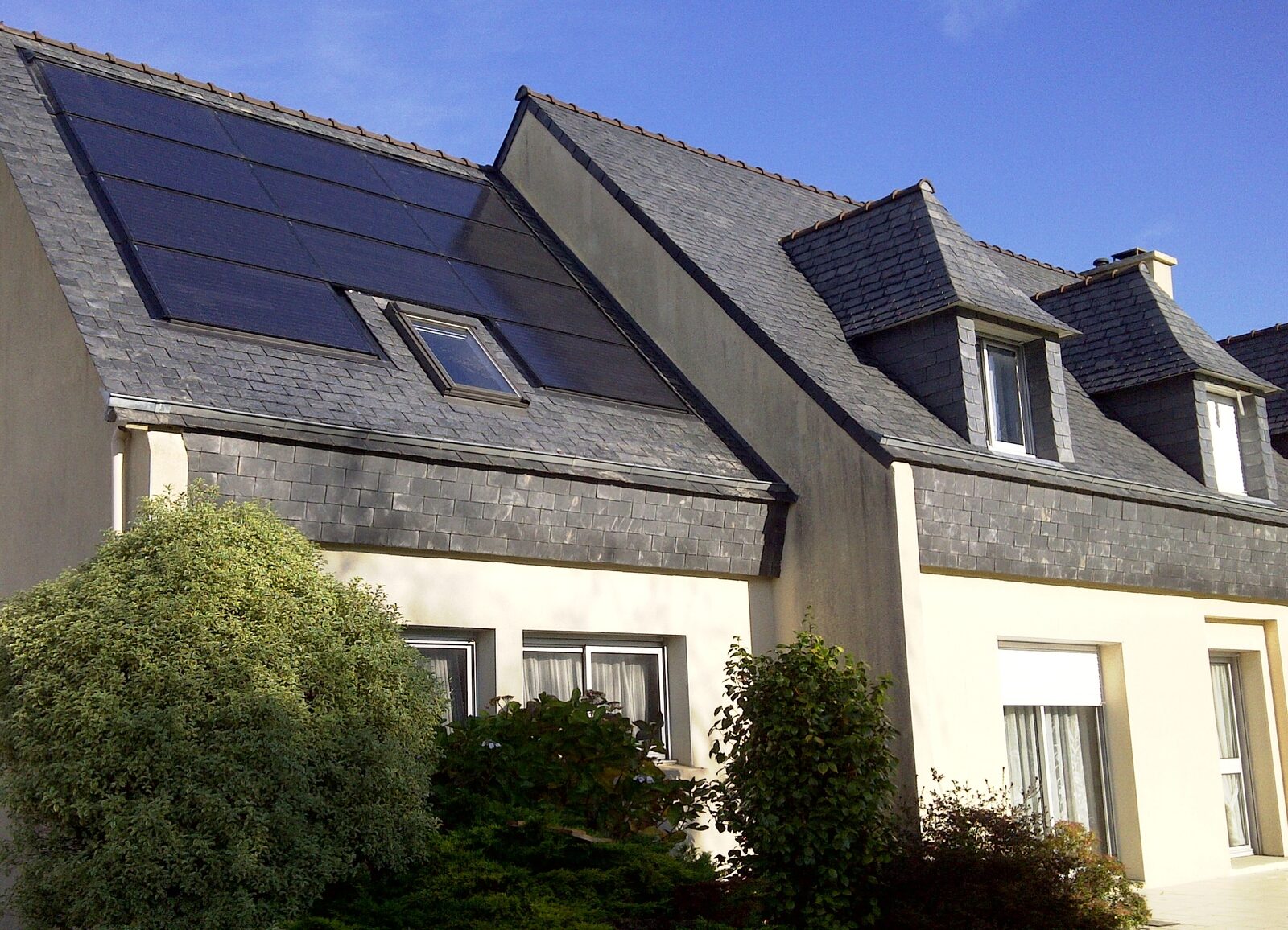 Einfamilienhaus mit dunklen Photovoltaikmodulen auf dem Schieferdach