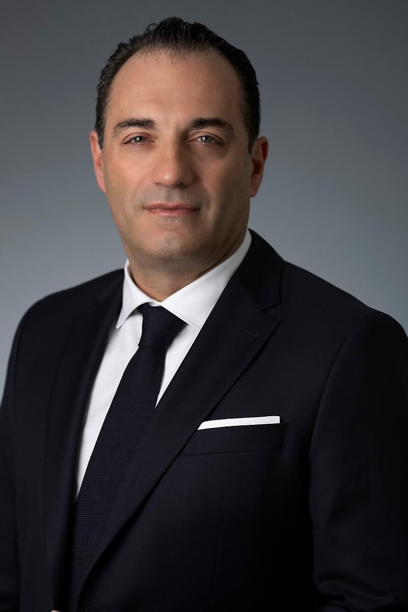 Stellantis CEO'su Antonio Filosa'nın gri fon önünde koyu takım elbiseli resmi portresi