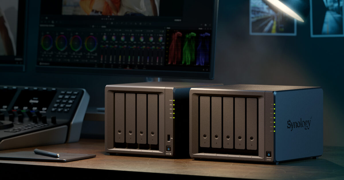 Zwei Synology-NAS-Gehäuse mit Laufwerkseinschüben auf einem Schreibtisch vor einem Monitor
