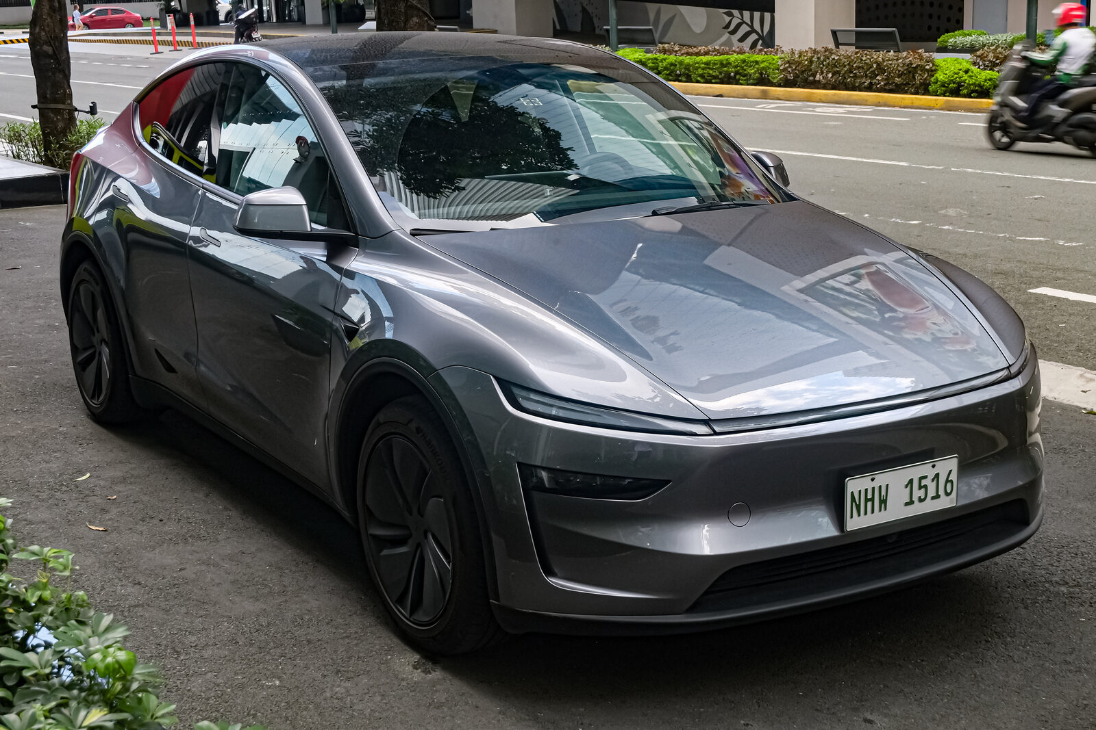 Gri renkli yeni kasa Tesla Model Y Long Range arkadan itiş, önden çapraz açıyla yol kenarında