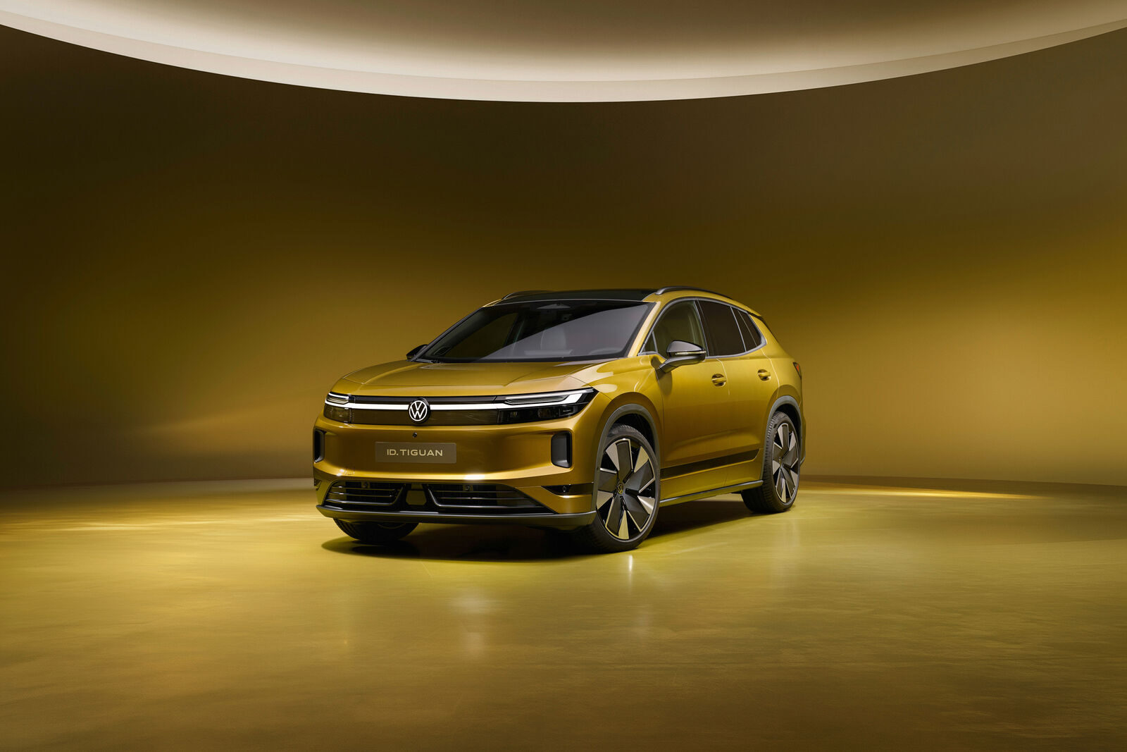 Goldfarbener VW ID. Tiguan in der Frontansicht mit durchgehender Lichtleiste in einem runden Studio