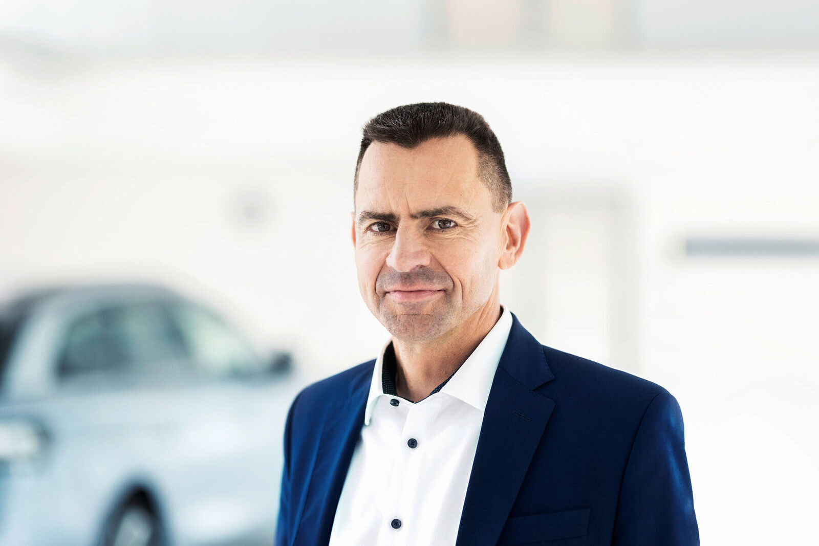 Porträt von Martin Sander, Vertriebsvorstand des Volkswagen-Konzerns, vor einem unscharfen Fahrzeug