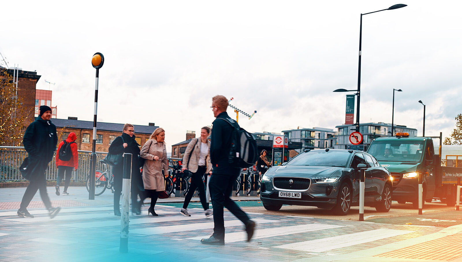 Ein Jaguar I-PACE mit Wayve-Technik wartet in London an einem Zebrastreifen, Fußgänger überqueren die Straße