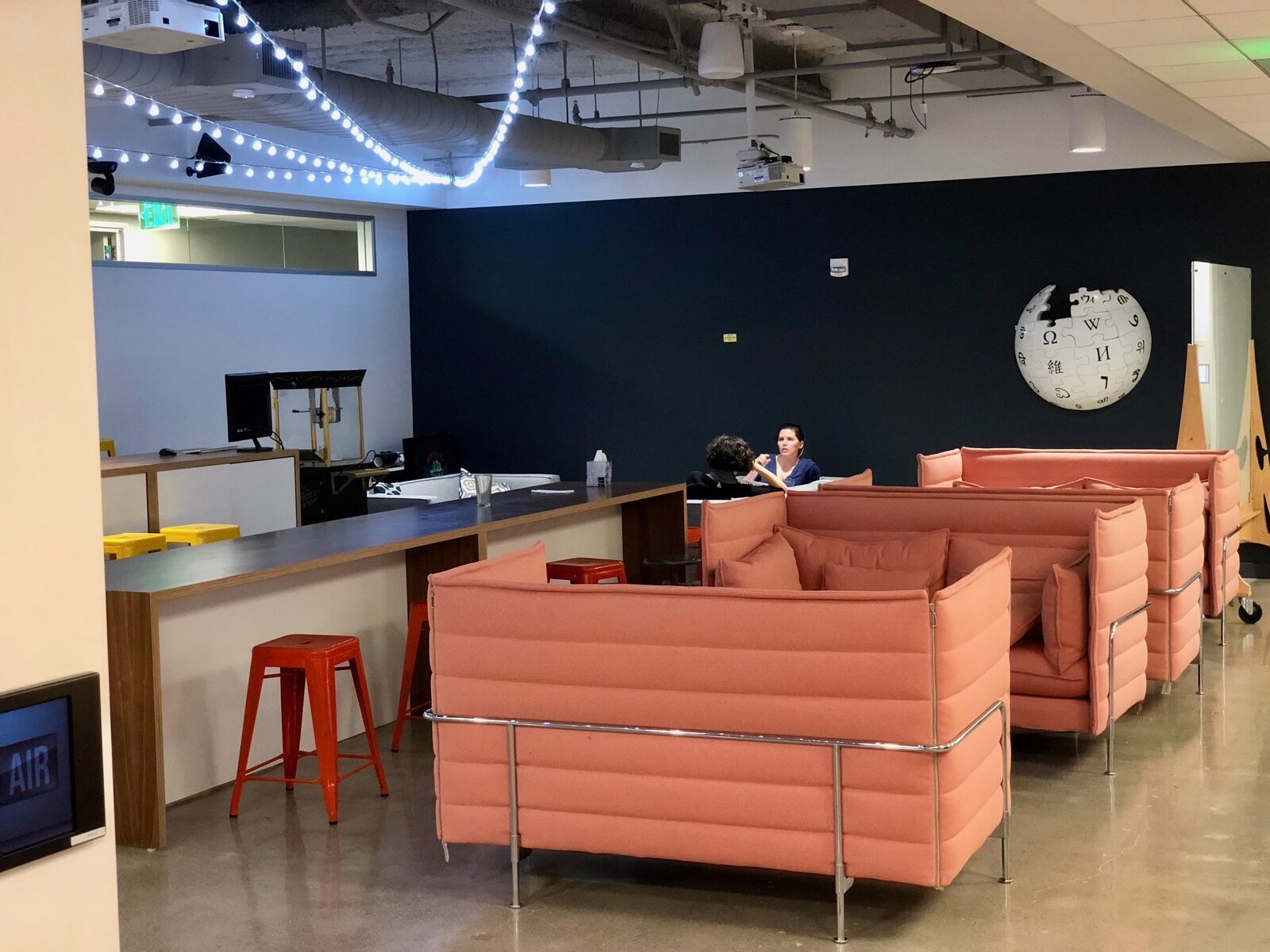 Lounge in het kantoor van de Wikimedia Foundation in San Francisco met roze banken en een Wikipedia-wereldbol aan de muur