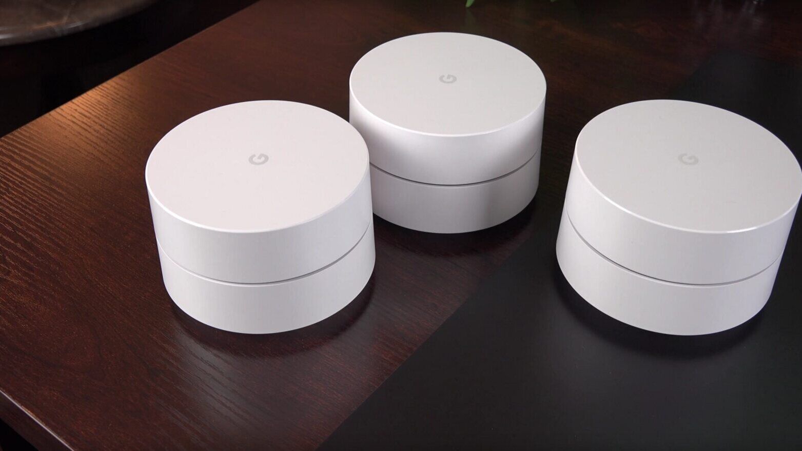 Drei weiße Google-WiFi-Mesh-Router auf einem Holztisch