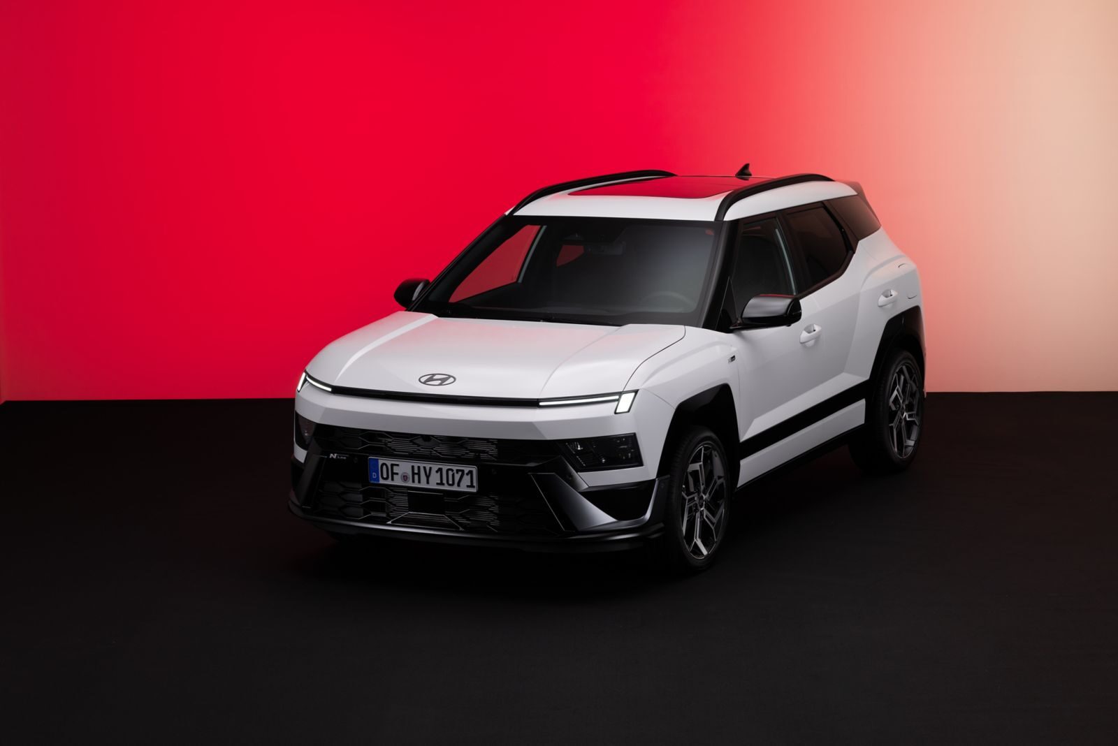 Beyaz renkli yeni nesil Hyundai Bayon N Line, kırmızı fon önünde önden çapraz görünüm