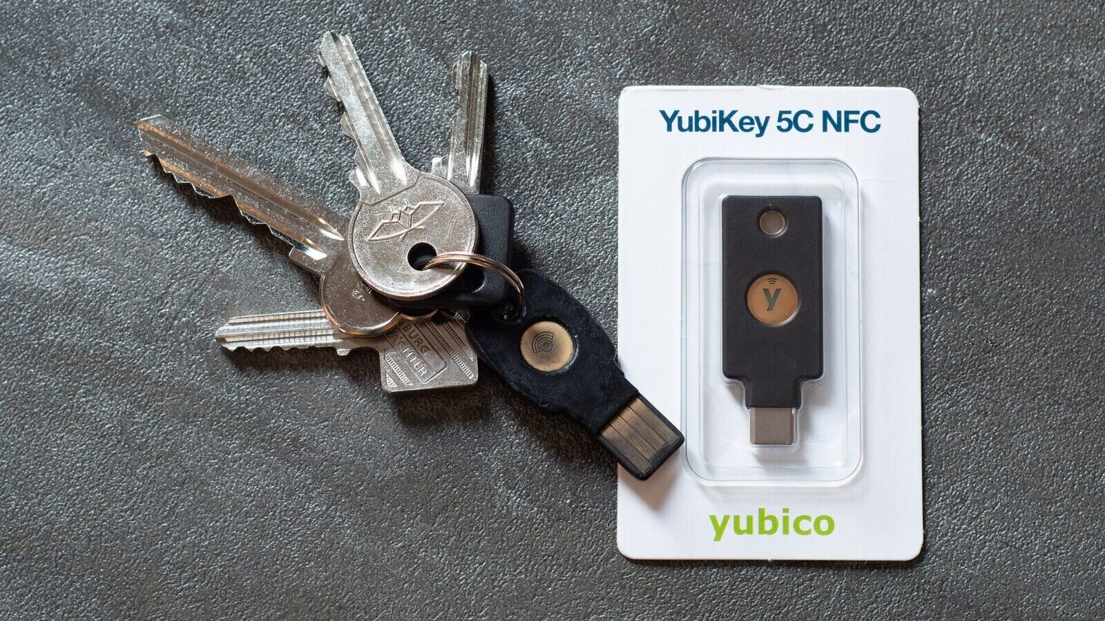 Anahtarlığa takılı bir YubiKey ve ambalajındaki YubiKey 5C NFC donanım güvenlik anahtarı
